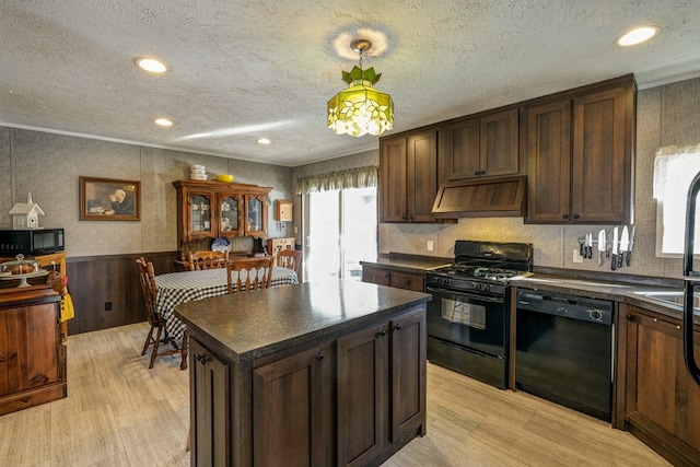 kitchen with hanging light fixtures, custom exhaust hood, a center island, black appliances, and light hardwood / wood-style flooring