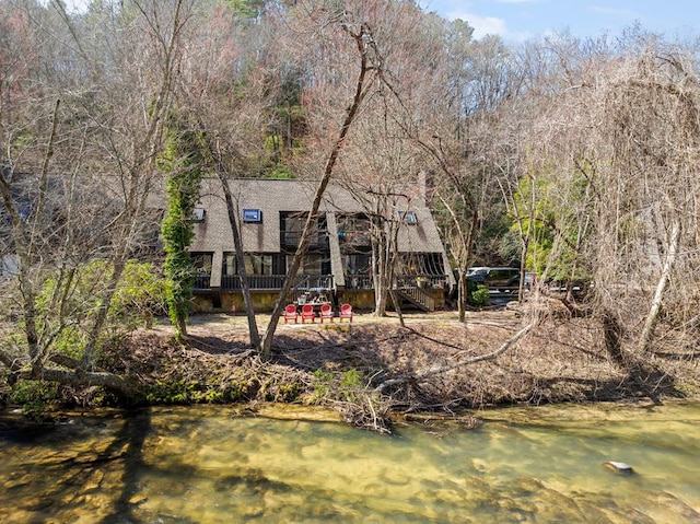 rear view of property with a view of trees and a water view