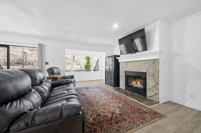 living area featuring a high end fireplace, a textured ceiling, and wood finished floors