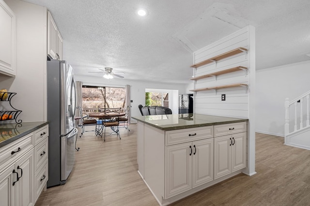 kitchen featuring white cabinets, stainless steel fridge, light wood finished floors, and a textured ceiling