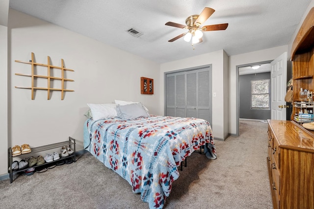 bedroom featuring light carpet, visible vents, a textured ceiling, and a closet