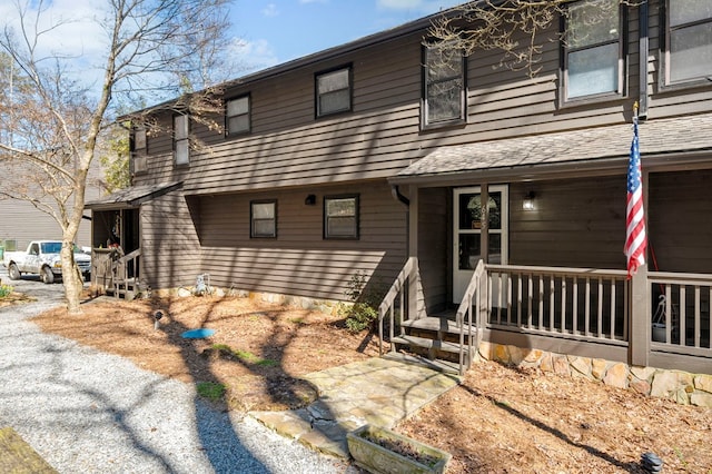 view of property with a porch and a shingled roof