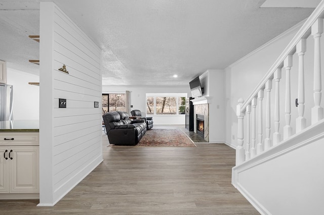 interior space featuring a textured ceiling, stairway, light wood-style floors, crown molding, and baseboards