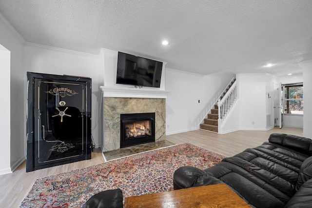 living room with a high end fireplace, stairway, crown molding, and wood finished floors