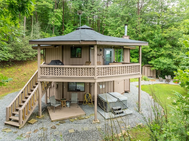 back of house featuring a wooden deck, a patio, and a hot tub