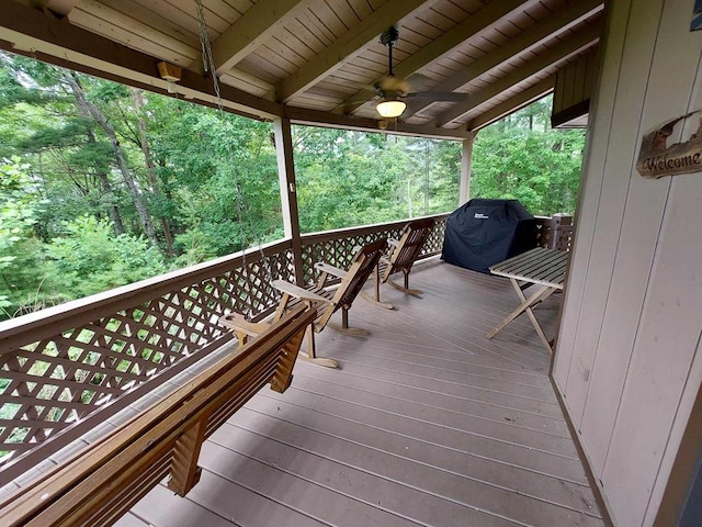 deck with a view of trees, a ceiling fan, and grilling area