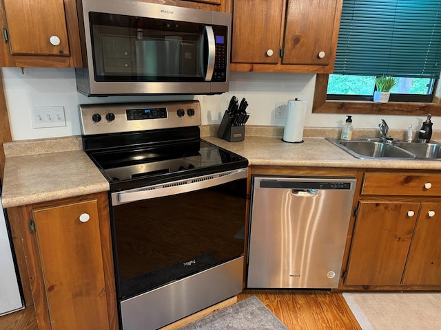 kitchen featuring light countertops, brown cabinetry, appliances with stainless steel finishes, and a sink