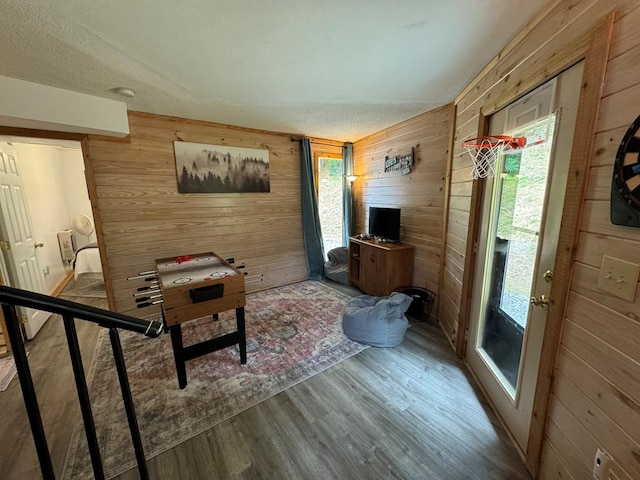 interior space with wooden walls, wood finished floors, and a textured ceiling