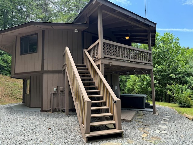 exterior space featuring a wooden deck, a ceiling fan, stairs, and a hot tub