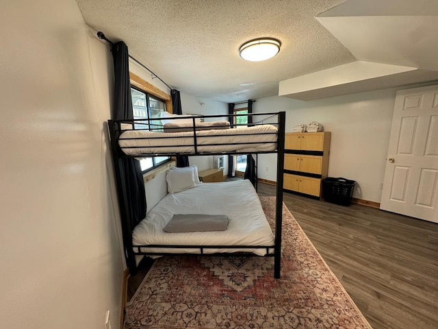 bedroom featuring a textured ceiling, dark hardwood / wood-style flooring, and lofted ceiling