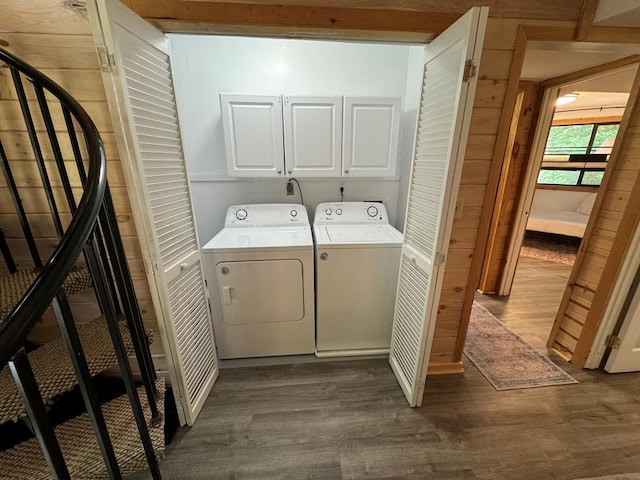 laundry room with wood walls, cabinets, hardwood / wood-style flooring, and washing machine and clothes dryer