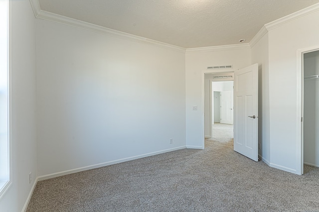 unfurnished bedroom featuring ornamental molding, light colored carpet, and a textured ceiling