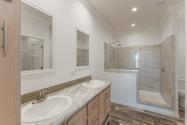 bathroom with ornamental molding, wood-type flooring, and a tile shower