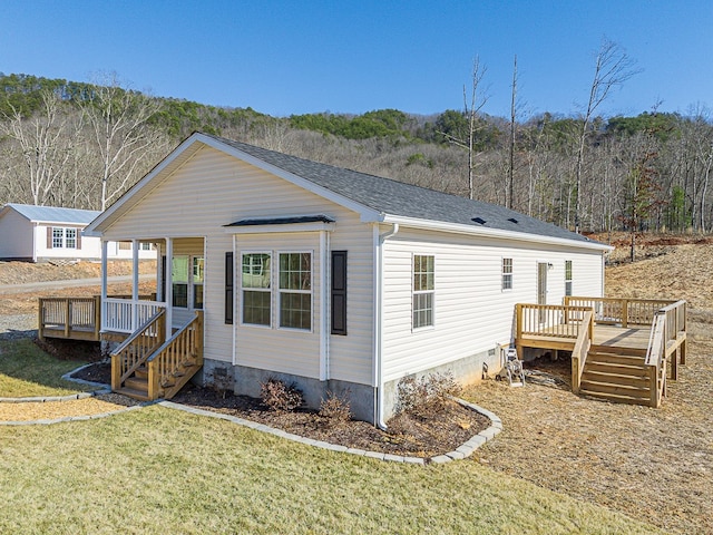 back of property with a wooden deck and a lawn