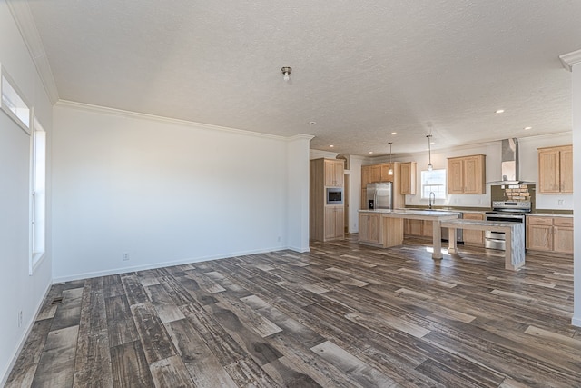 kitchen featuring appliances with stainless steel finishes, sink, a center island, dark wood-type flooring, and wall chimney exhaust hood