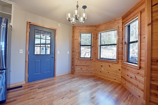 foyer featuring a notable chandelier, light hardwood / wood-style flooring, and wood walls