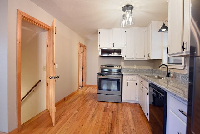 kitchen with sink, white cabinetry, light stone counters, light hardwood / wood-style flooring, and appliances with stainless steel finishes