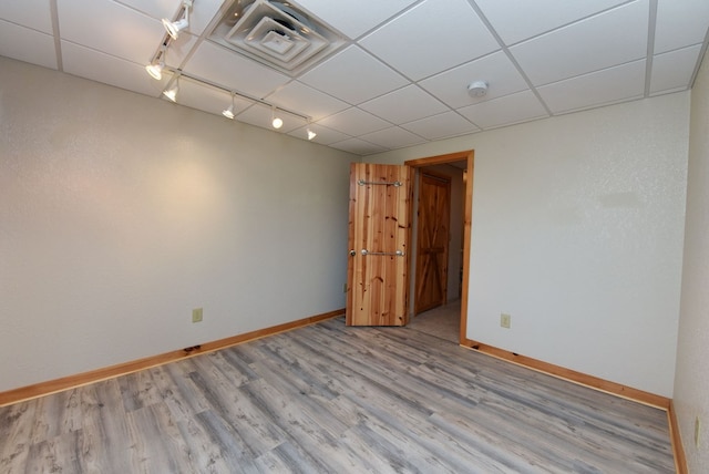 spare room with rail lighting, hardwood / wood-style floors, and a drop ceiling