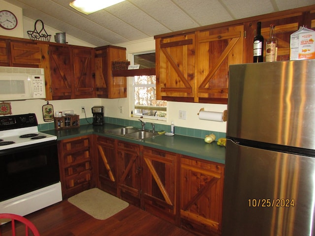 kitchen with white appliances, vaulted ceiling, dark wood-type flooring, and sink