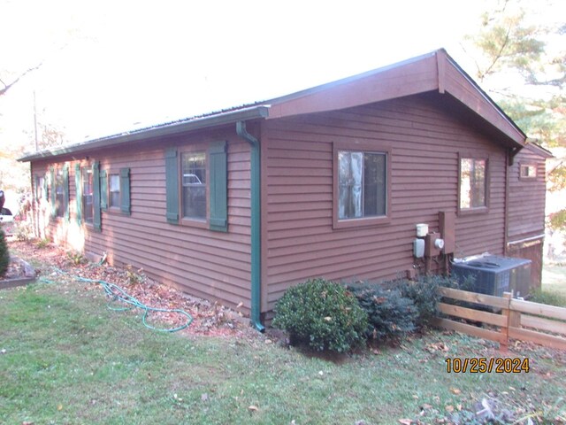 view of property exterior with central air condition unit and a lawn