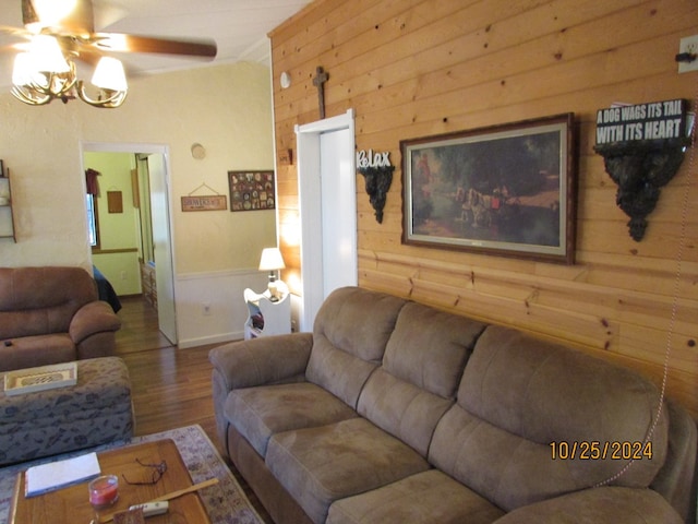 living room featuring wood walls, wood-type flooring, vaulted ceiling, and ceiling fan