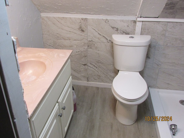 bathroom featuring tile walls, vanity, hardwood / wood-style floors, and toilet