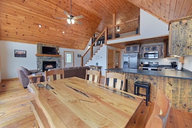 dining room with stairs, light wood-type flooring, a fireplace, and wooden ceiling