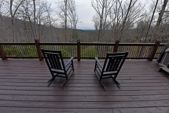 wooden terrace featuring a wooded view