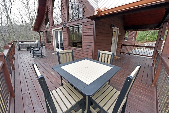 wooden terrace featuring a hot tub, outdoor dining area, and french doors