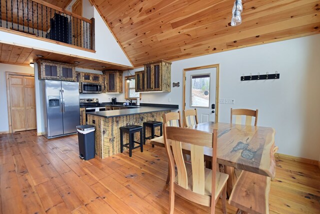 kitchen with dark countertops, light wood-style flooring, appliances with stainless steel finishes, wooden ceiling, and a peninsula