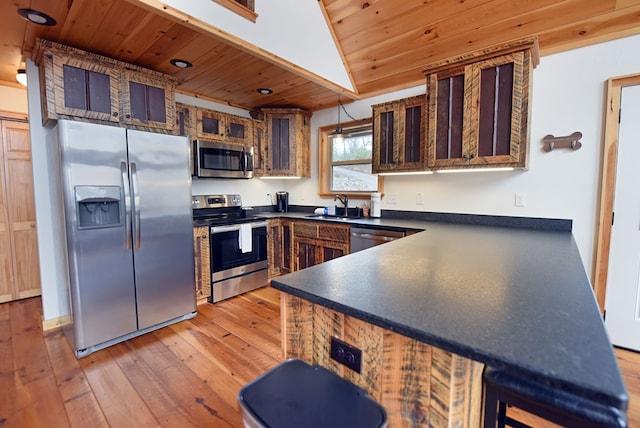 kitchen featuring wooden ceiling, stainless steel appliances, a sink, light wood finished floors, and dark countertops