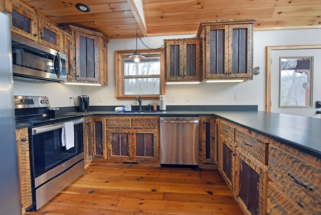 kitchen with stainless steel appliances, dark countertops, wood ceiling, and a sink