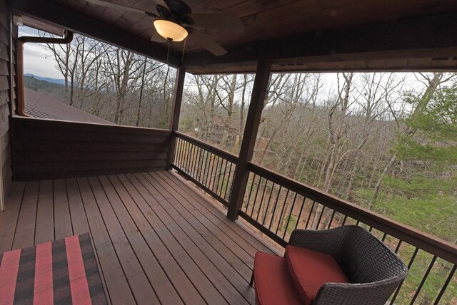 wooden terrace featuring ceiling fan and a forest view