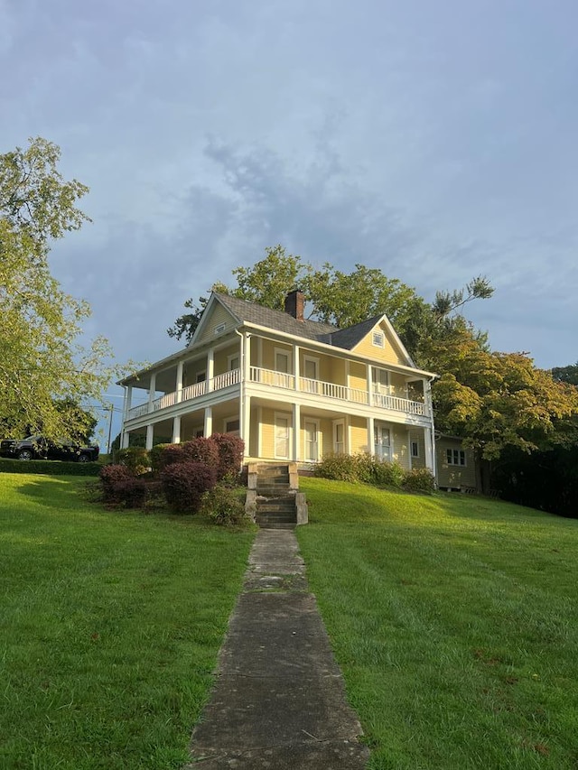 greek revival inspired property with a balcony and a front yard