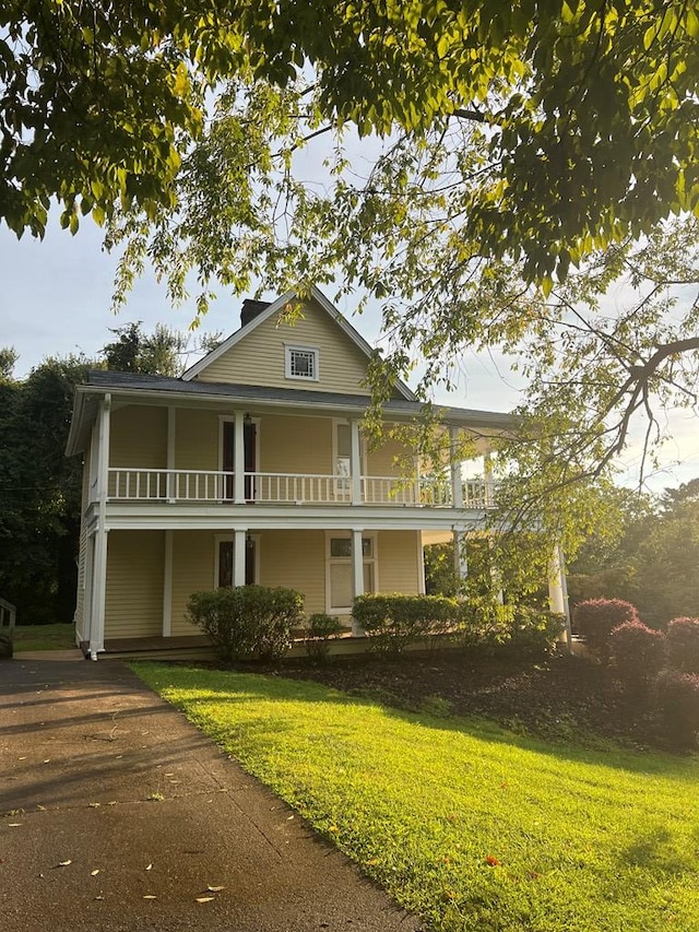 farmhouse-style home featuring a front yard and a balcony