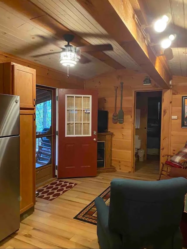 living room with light hardwood / wood-style flooring, ceiling fan, and wood walls