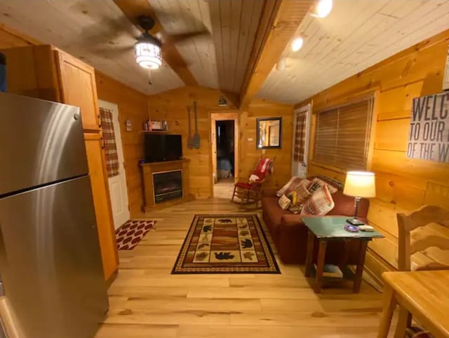 living room featuring light hardwood / wood-style flooring, lofted ceiling, wood walls, and ceiling fan