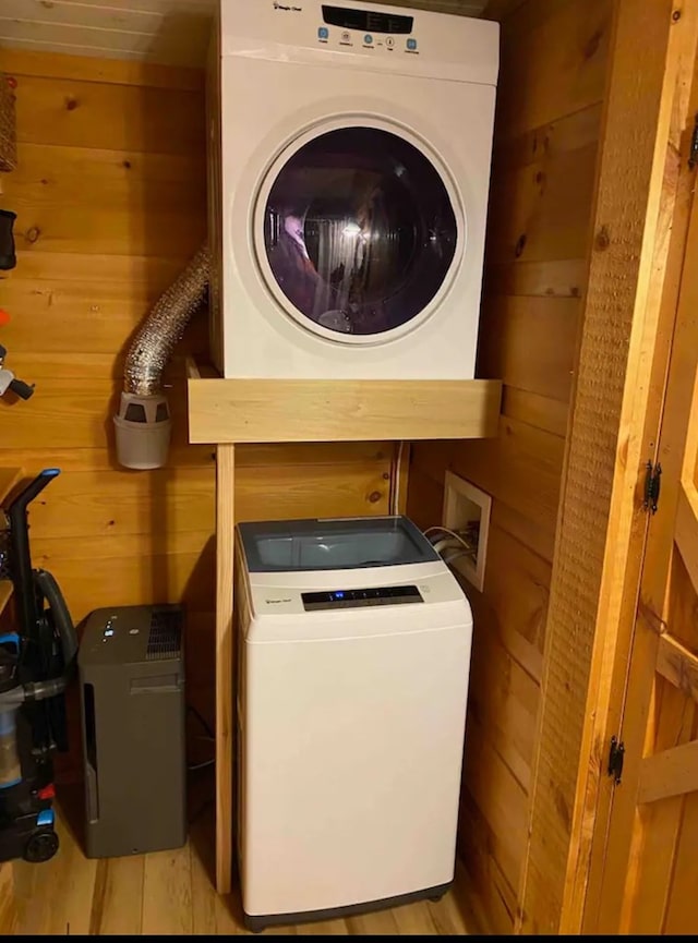 laundry area with washer / dryer, light wood-type flooring, and wood walls