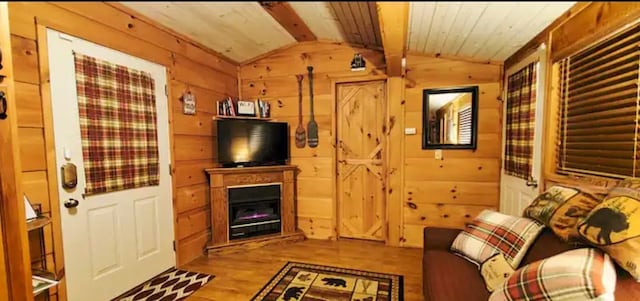 living room with wood ceiling, lofted ceiling with beams, light wood-type flooring, and wooden walls