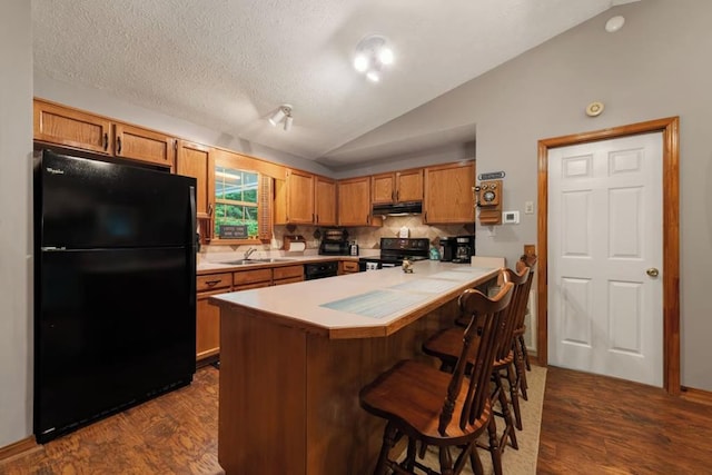 kitchen with black appliances, lofted ceiling, sink, kitchen peninsula, and dark wood-type flooring