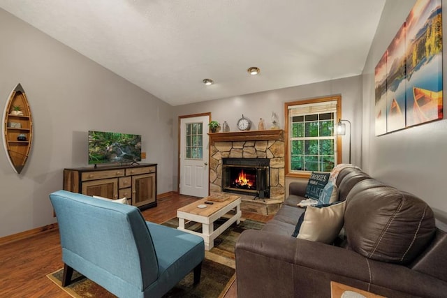 living room featuring lofted ceiling, a stone fireplace, and wood-type flooring