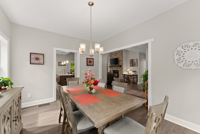 457 Celie Ann Seabolt Rd, Cleveland, GA 30528 - dining room with wood finished floors, a chandelier, baseboards, and a stone fireplace