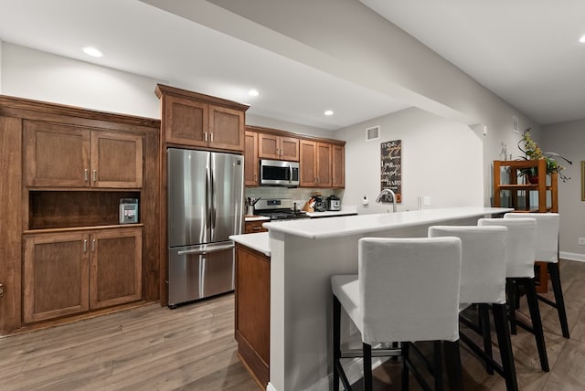 457 Celie Ann Seabolt Rd, Cleveland, GA 30528 - kitchen with appliances with stainless steel finishes, a kitchen breakfast bar, light wood-style flooring, recessed lighting, and backsplash