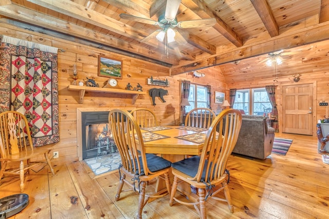 dining space featuring wood walls, wooden ceiling, ceiling fan, light wood-type flooring, and beam ceiling