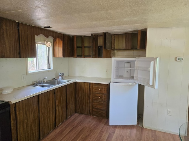 kitchen with light countertops, a sink, wood finished floors, and black range with electric stovetop