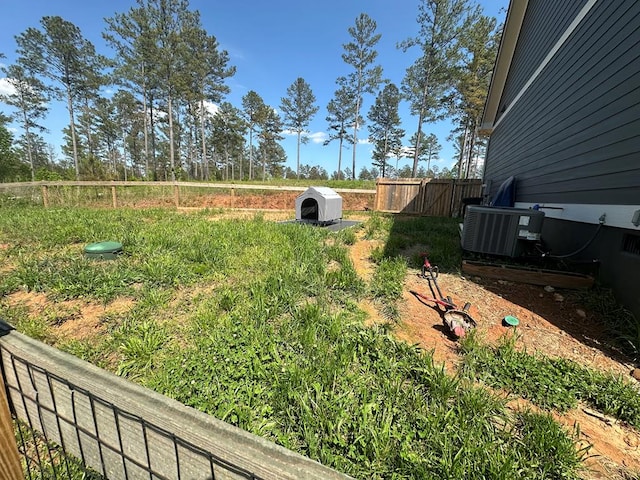 view of yard with central air condition unit and fence