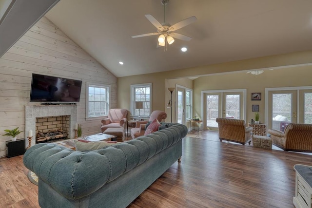 living area with a brick fireplace, high vaulted ceiling, wood finished floors, and french doors