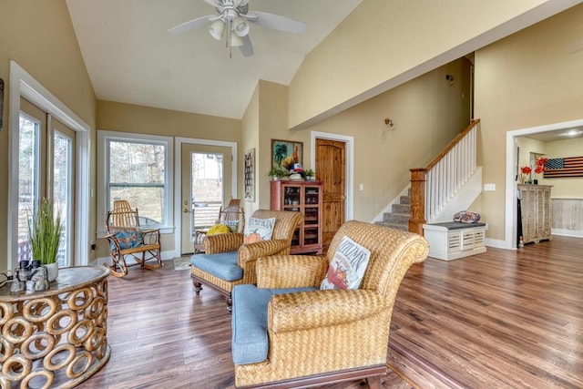 living area with high vaulted ceiling, a ceiling fan, wood finished floors, and stairs