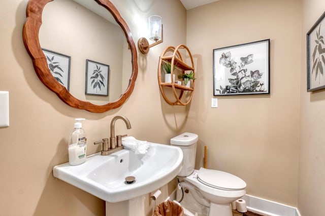 bathroom with toilet, baseboards, and a sink