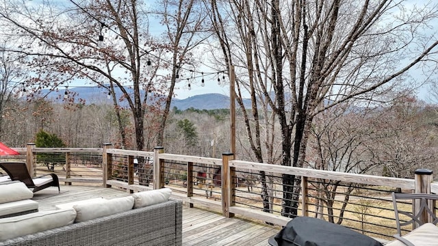 wooden terrace with outdoor lounge area and a view of trees